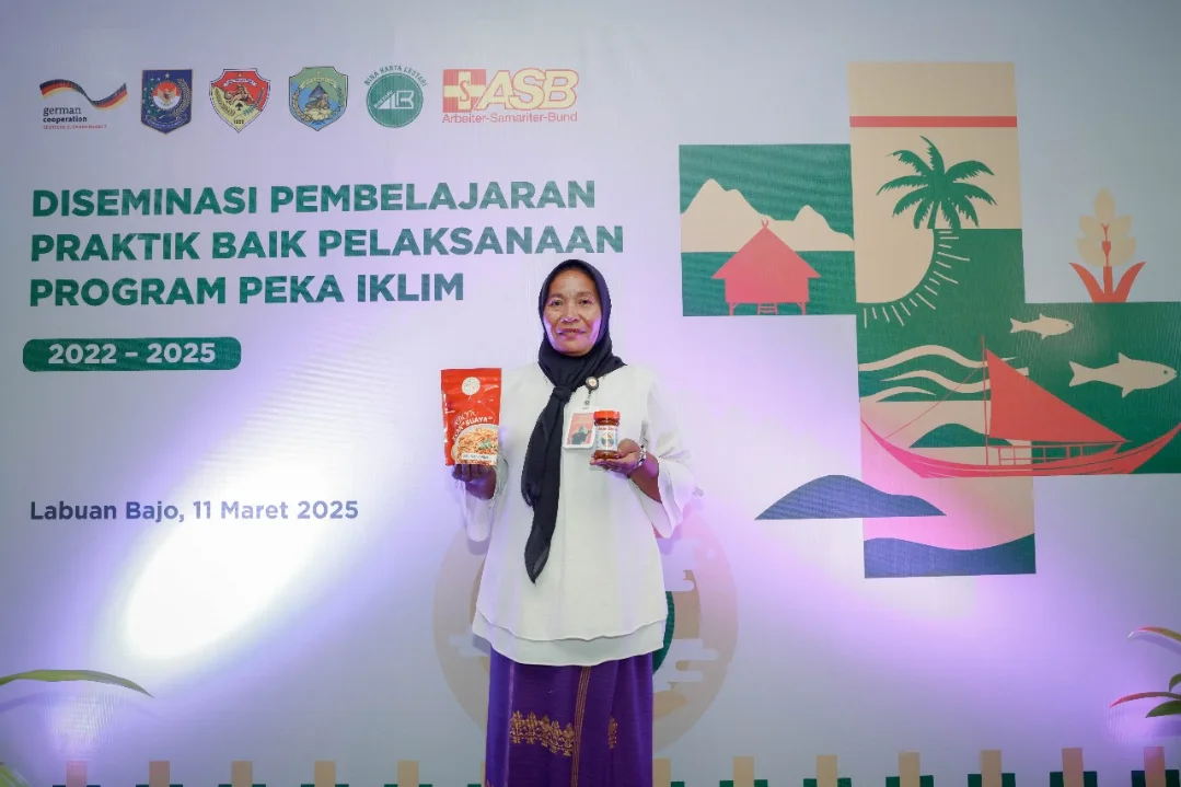Mrs Saripa holding two local fish-based products, smoked fish chili paste and crocodile fish floss, at the closing event of the PEKA IKLIM project.