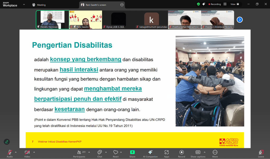 A screenshot of a webinar slide explaining disability as a dynamic concept, defined by the interaction between people with functional difficulties and environmental or attitudinal barriers. The slide includes a group photo of three men—one using a wheelchair—in a close huddle, participating in a group activity. The session is part of ASB’s Disability Inclusion webinar in collaboration with the Ministry of Housing and Settlement Areas (Kementerian PKP), Indonesia.