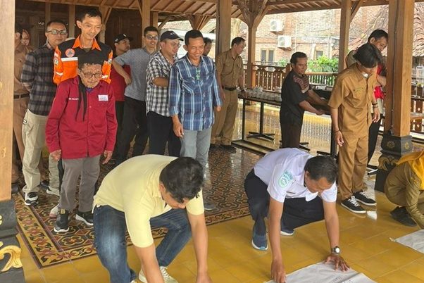 Peserta duduk berkelompok di dalam ruangan, berdiskusi sambil menuliskan hasil diskusi pada kertas hasil kerja. Susana hangat dan partisipatif menunjukkan keterlibatan aktif peserta dari berbagai latar belakang.
