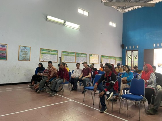 Sekelompok orang berkumpul di dalam ruangan duduk di kursi yang berwarna biru menyaksikan acara peresmian penampungan air atau water system di Desa Giritengah. Peserta di dalamnya merupakan perwakilan dari masyarakat. Suasana terlihat sangat khidmat.